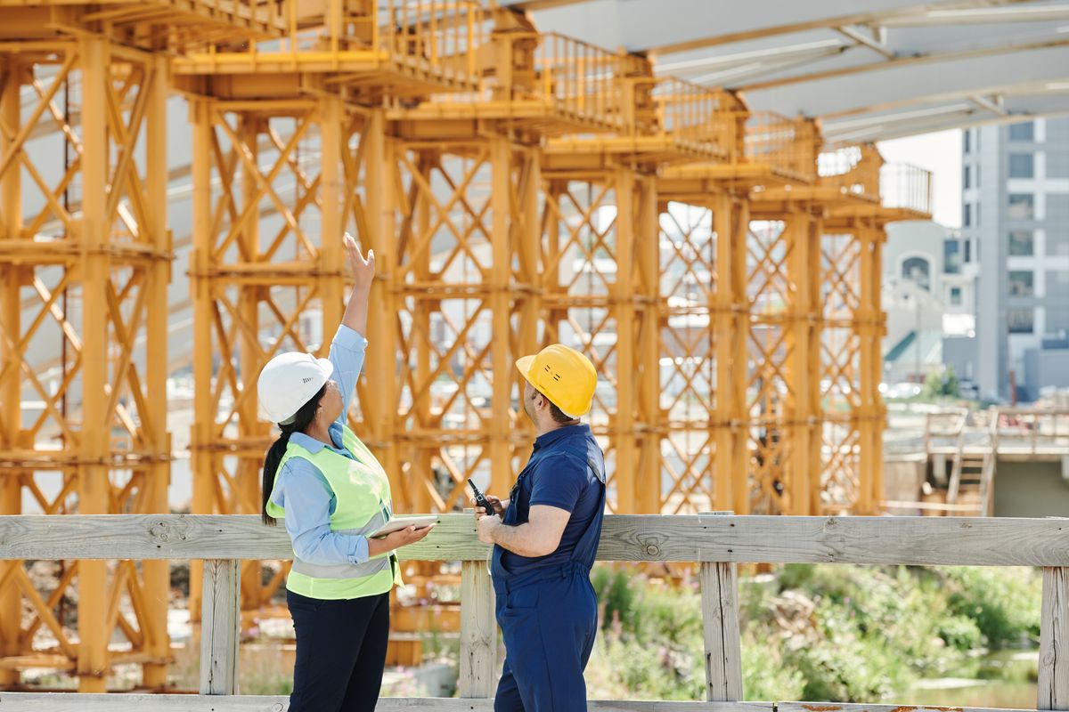 An Alberta field worker in hi-vis gear standing in warm natural light, calmly checking his phone on a break